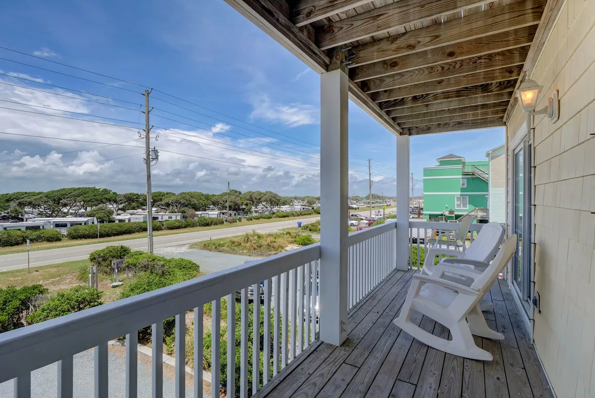 An exterior porch featuring classic rocking chairs, offering a tranquil spot to relax and soak in the surrounding natural landscape. The porch provides a seamless connection between the indoors and the outdoors, perfect for unwinding while your dog enjoys the fresh beach air.