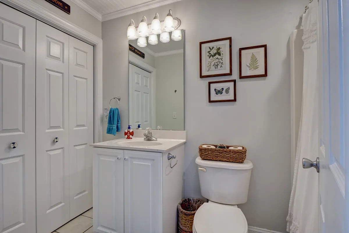 A modern, serene bathroom featuring a spacious vanity with a sink, a mirrored wall, framed art, a toilet, and a towel rack. The clean, calm design enhances a relaxing experience for morning and bedtime routines.