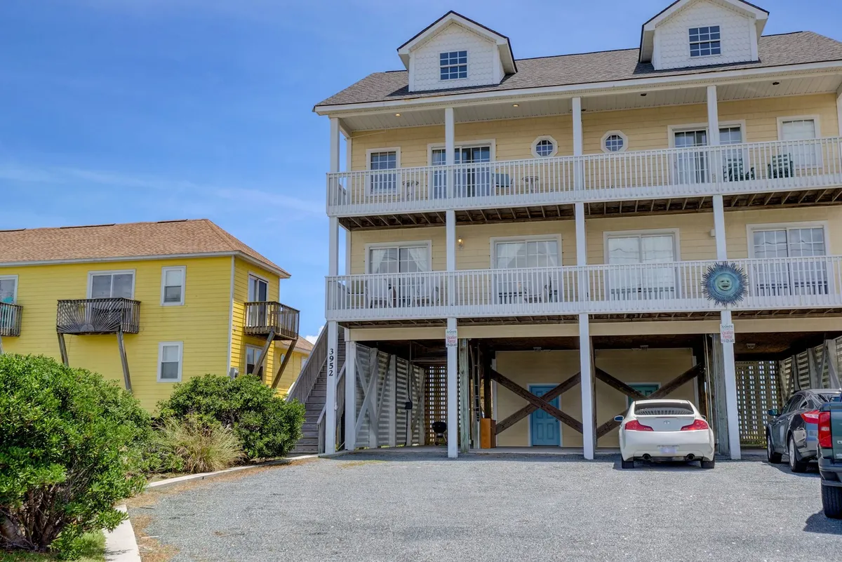 A cheerful exterior shot of the multi-level house, complete with blue door and balconies. The image hints at private beach access and showcases the spacious, pet-friendly environment awaiting guests and their furry companions.