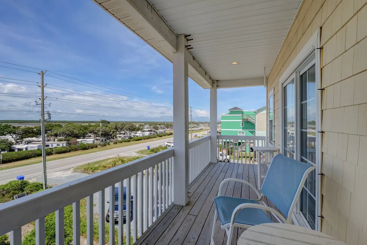 A peaceful balcony scene with a blue chair overlooking the neighborhood and road. The balcony offers a quiet retreat to take in the sunset or sip drinks after beach walks with your pet.